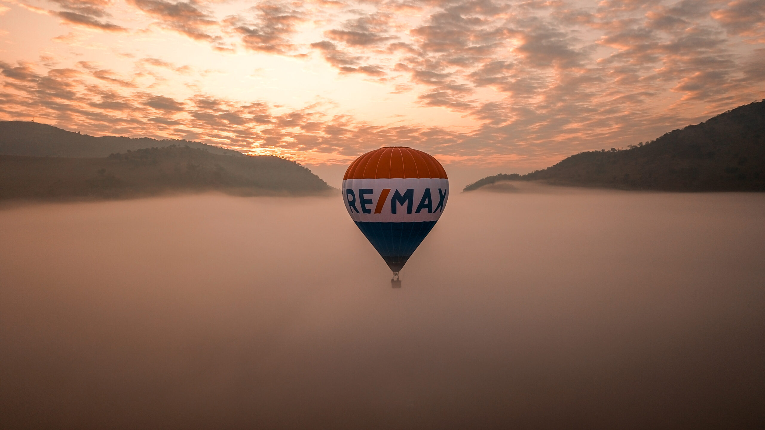 Remax name ballon in the air with fog and mountains around it