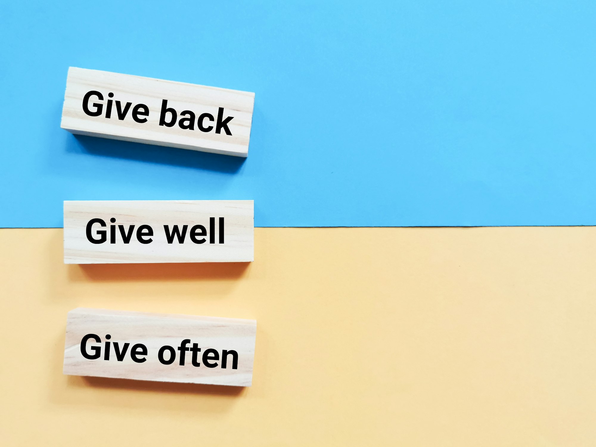 Quote give back give well and give often written on wooden blocks. how remax is giving back to their community